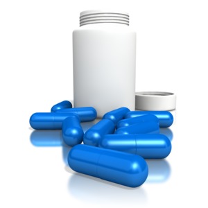 This image contains a white blank pill bottle with blue pills spread out on ground.