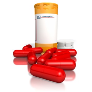 This image contains a white blank pill bottle with red pills spread out on ground.