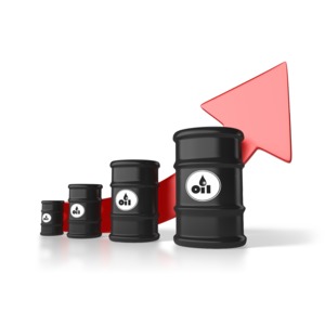 An image of the rising cost of a barrel of oil. A group of four oil barrels get larger and a red arrow behind them indicate a raising trend.