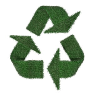 An image of the recycling symbol covered in a lush field of grass.  An environmental awareness concept.