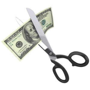 An image of a hundred dollars being cut up by a pair of scissors.