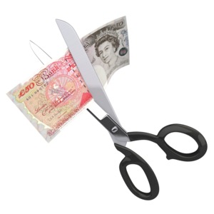 An image of fifty British pounds being cut up by a pair of scissors.