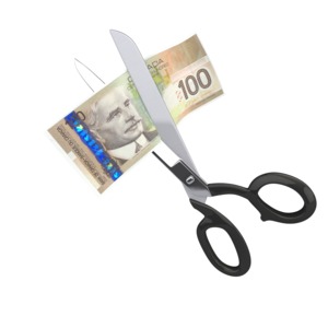 An image of one hundred British Pounds being cut up by a pair of scissors.