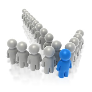 This clip art image shows many gray stick figures standing in a formation of an arrow with the front figure colored blue.