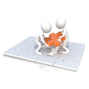 This clip art image shows two stick figure working together to place a missing piece in the puzzle.  This graphic shows the concept of using teamwork to complete a task.