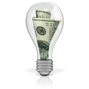This clip art image shows a clear light bulb with hundred dollar bills stuck in it.  This graphic displays a concept of energy savings, waste of electricity, and business wealth.