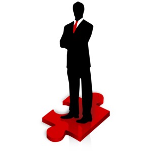 An image of a businessman standing on a red puzzle piece.