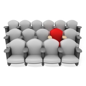 A single theater seat is isolated in red amidst rows of grey chairs.  A concept of a reserved seat, or the best seat in the house.  Auditorium or theater seating.
