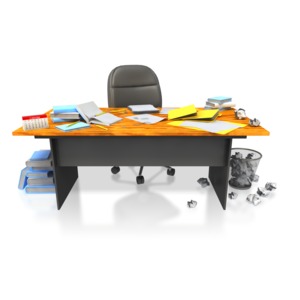 This image shows a office desk that is disorganized and full of clutter.