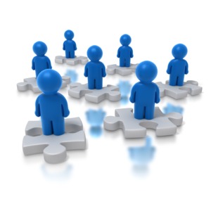 A group of stylized figures each stand on a puzzle piece.  A concept of a diverse group of talents or available human resources to solve a problem.  This business illustration could also be used as a concept of a problem which needs a solution, or how do we all fit together? 