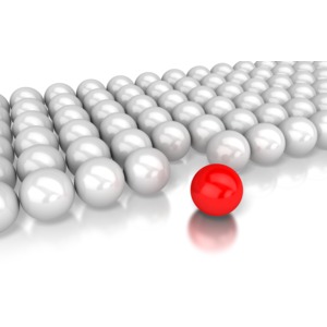 A single red ball is set apart from rows of gray balls behind it in a concept of volunteering or stepping forward.
