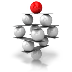 A stack of shiny metallic balls are stacked precariously on top of each other in a concept of keeping everything in balance or in harmony.