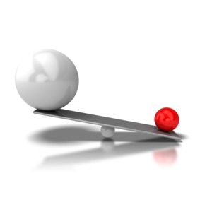 A small red ball lifts a large ball on a scale.  A concept of having an advantage or the underdog beating the giant.