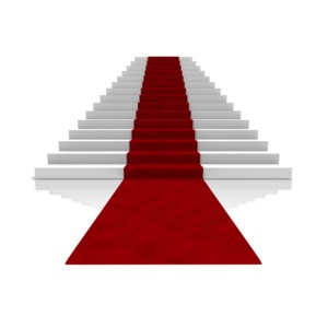 An image of a large set of stairs with a red carpet streaming down.