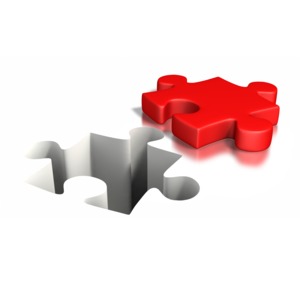 An image of a puzzle piece laying next to its own cutout in ground.