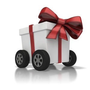 A gift box on wheels with a red ribbon.  A concept of delivering or shipping a gift.
