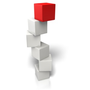 An image of a stack of boxes balancing on top of one another with a colored one on top.