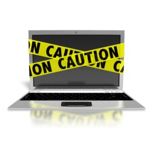 An image of a laptop wrapped with caution tape.