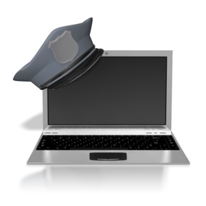 An image of a laptop with a police hat resting on the corner.