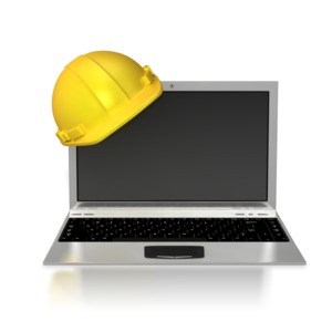 A hard hat resting on the corner of a laptop.