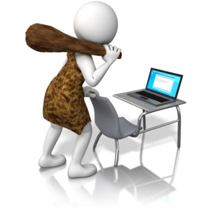 A caveman is shown standing in front of a laptop.