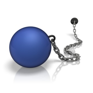 A colored weight ball secured to a wall by a chain.