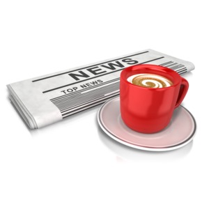 An image of a cup of coffee by a newspaper.