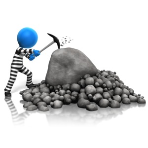 An inmate is shown doing hard labor by chipping away at rocks.