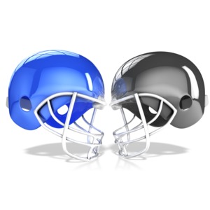 Two football helmets are shown about to collide into each other.
