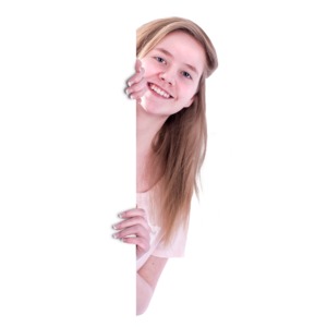 A teen girl peeks from behind a blank wall.