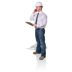 A construction foreman holds a clipboard as he talks on his cellphone.