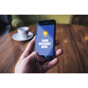 A hand holds a mobile phone. You can change the message on the phone using our on-line tools.