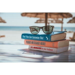 Three books are stacked on a table on the beach in a tropical location. You can customize the book titles using our on-line tools.