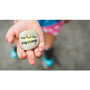 A girl holds a stone in her hand with your custom design on it.