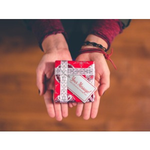 A pair of hands hold a Christmas gift with a gift tag. You may customize the message on the gift tag using our on-line tools.