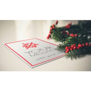 A Christmas card lies with some evergreen and red berries. You may customize the face of the card using our on-line tools.