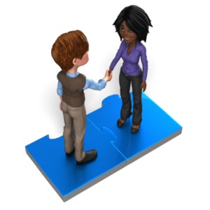 A business man and woman stand on puzzle pieces joined together.