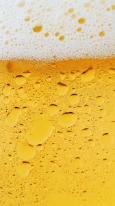 A close-up of a frothy beer glass with condensation and bubbles. 

