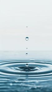 A tranquil image of water droplets creating ripples in a calm body of water, evoking serenity.


