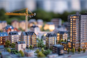 A miniature cityscape with illuminated buildings and a construction crane, symbolizing urban development.

