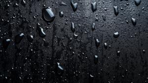 A close-up of water droplets on a dark surface, creating a sleek and modern aesthetic. 

