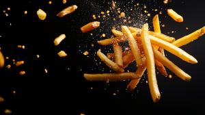 This image showcases flying french fries against a dark background, emphasizing their crispy texture and appeal.

