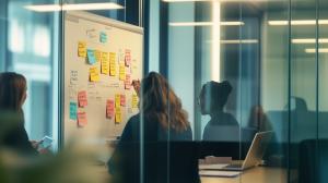 This image depicts a corporate meeting with individuals brainstorming on a whiteboard filled with sticky notes.

