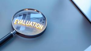 This image shows a magnifying glass over the word &quot;EVALUATION,&quot; symbolizing analysis and assessment.

