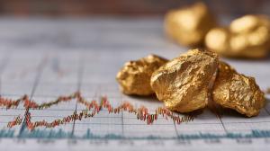 This image depicts gold nuggets on a financial chart, symbolizing investment in precious metals.

