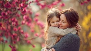 A heartwarming image of a mother embracing her daughter among blooming flowers, symbolizing love and connection.

