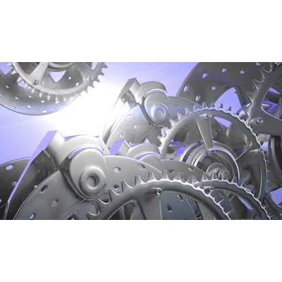 An assembly of mechanical gears turning in front of a bright light.