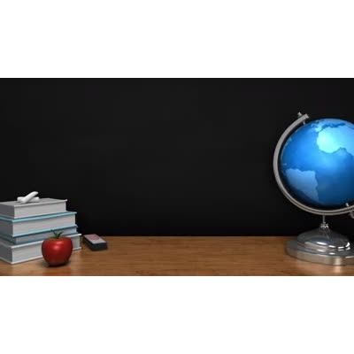 A globe spins in on a teachers desk in front of a blackboard.